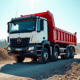 Camion benne neuf en chantier avec bras levé et ouvriers